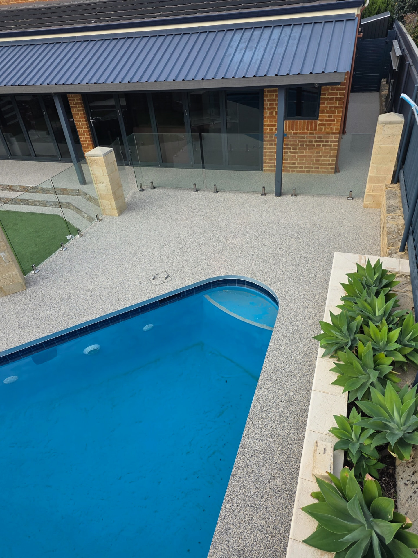 Cream resin bound pool surround Perth with glass fencing