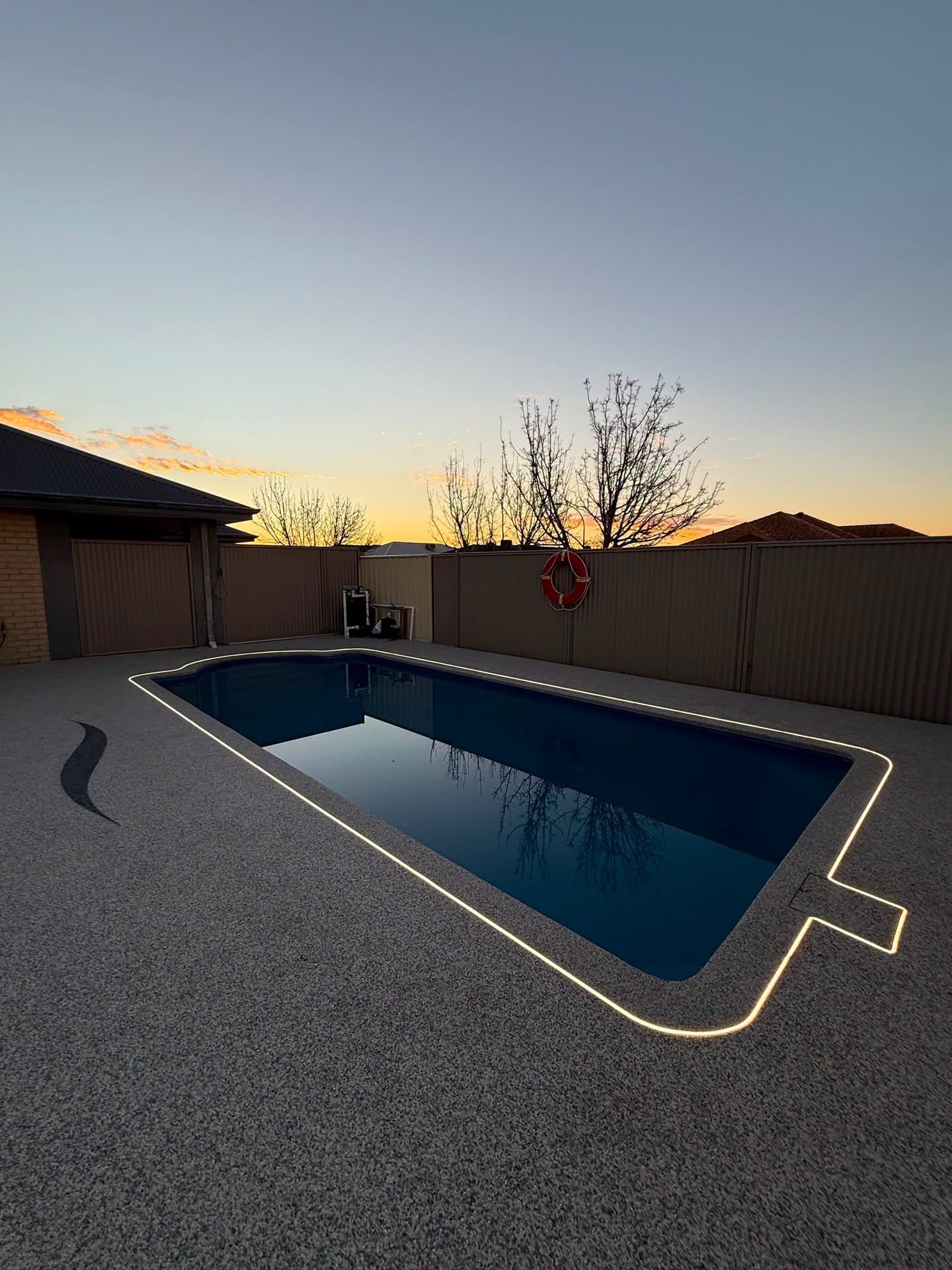 Resin bound pool deck Perth at dusk with LED perimeter lighting