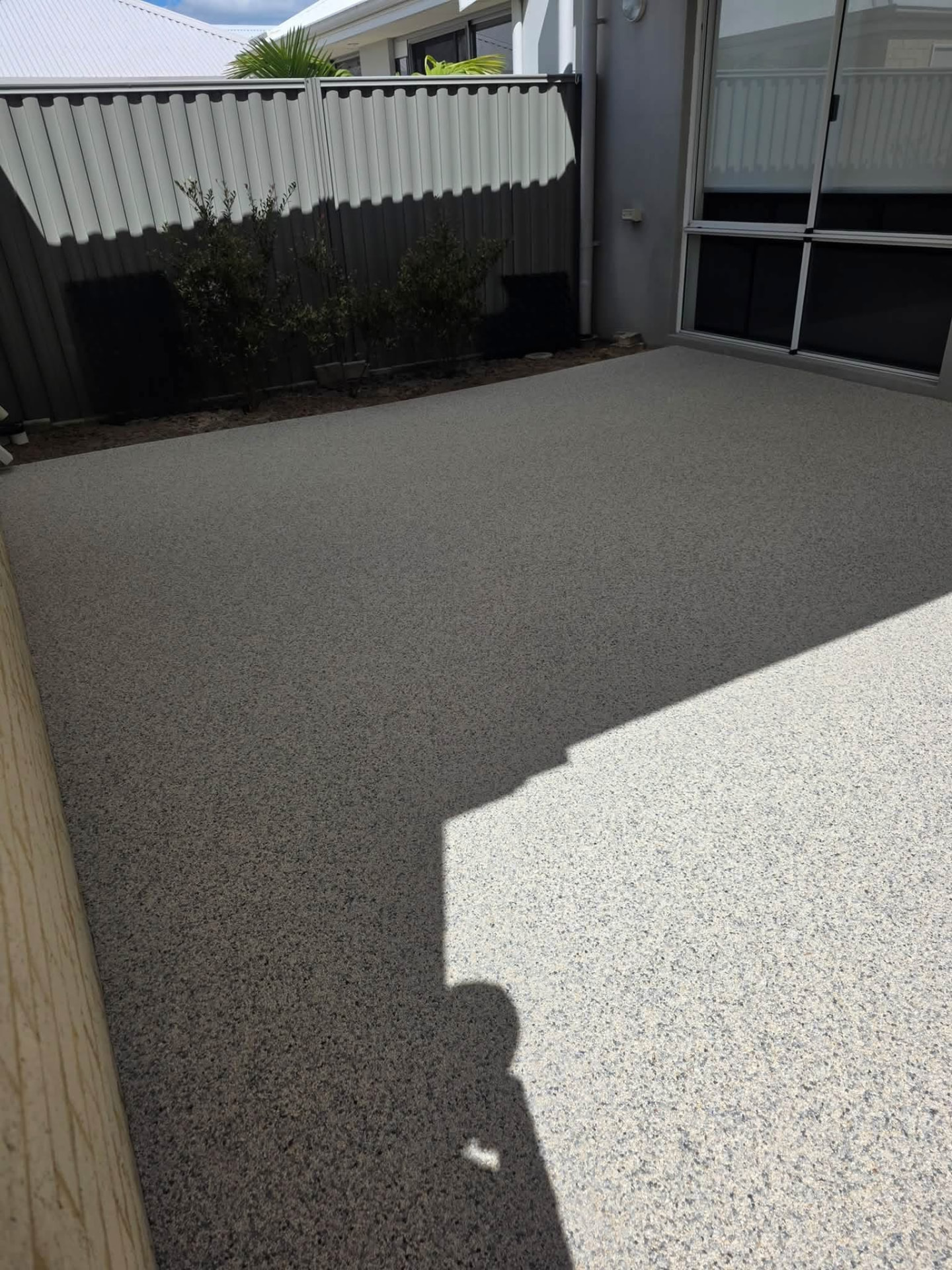 Resin bound courtyard patio beside sliding doors and garden fence