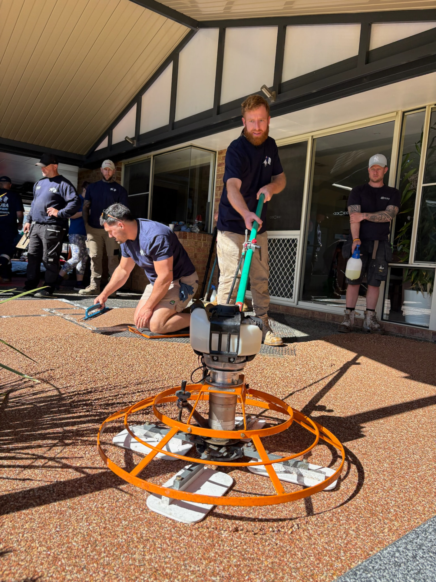 Installer using power trowel on resin bound surface during training