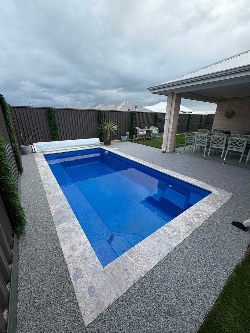 Grey resin bound pool surround with stone coping and outdoor dining area