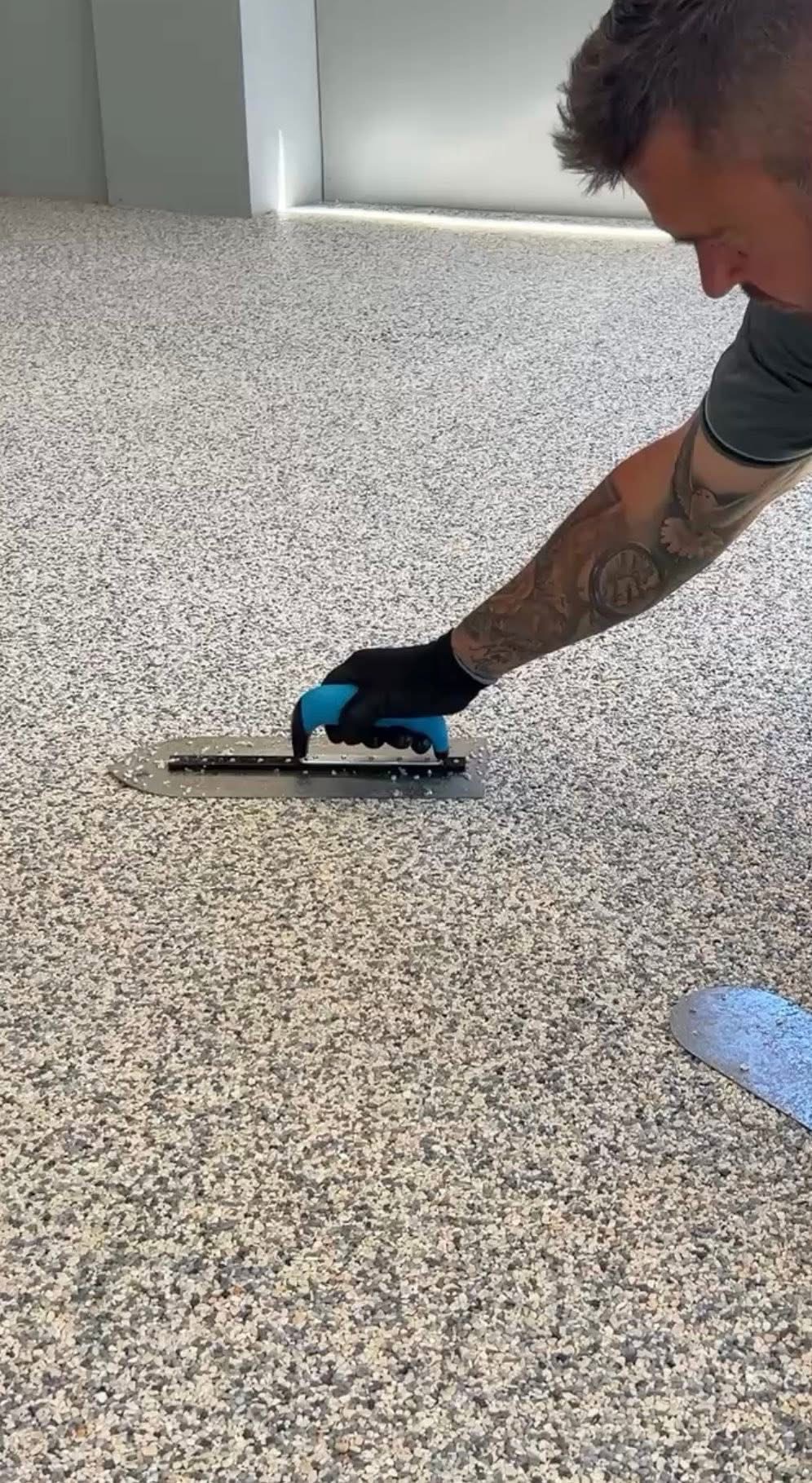 Installer smoothing resin bound surface with hand trowel