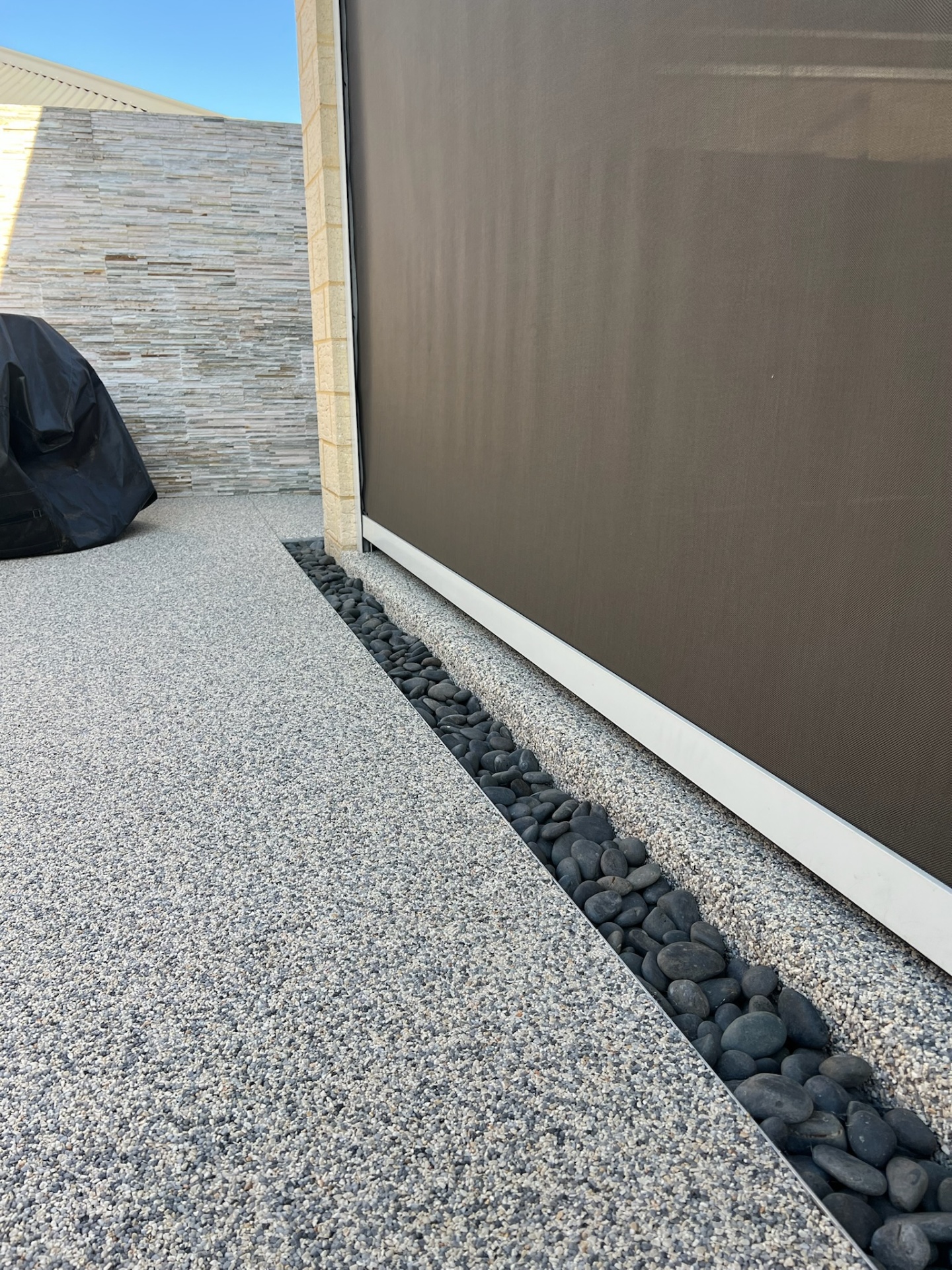 Resin bound surface with decorative pebble channel drainage