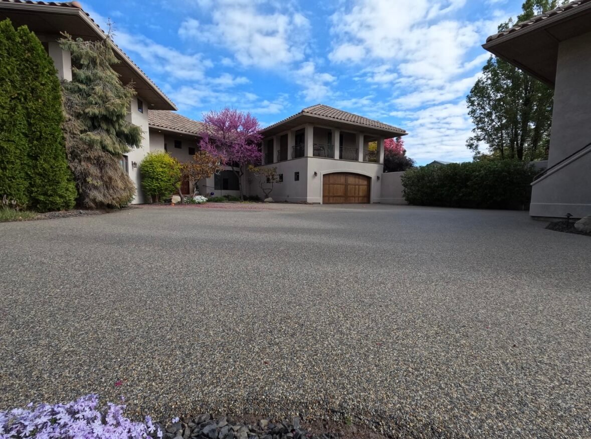 Resin bound driveway with Mediterranean-style home and blossom trees