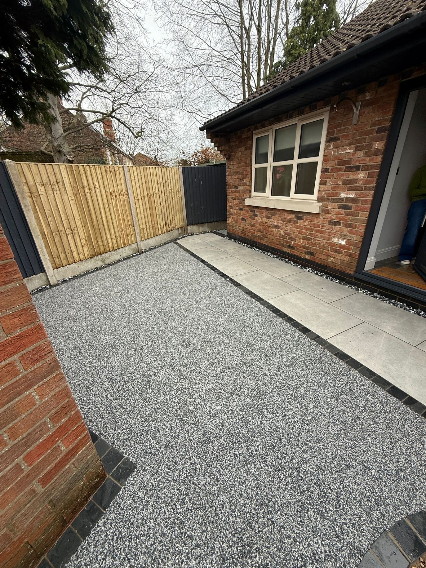 Resin bound grey patio with block edging and brick house