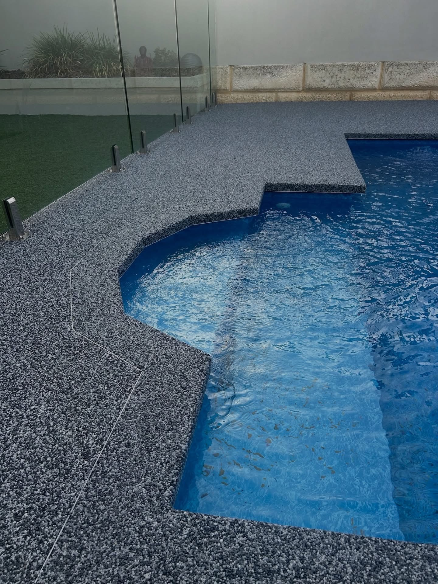 Grey flake resin bound pool coping Perth with glass fencing
