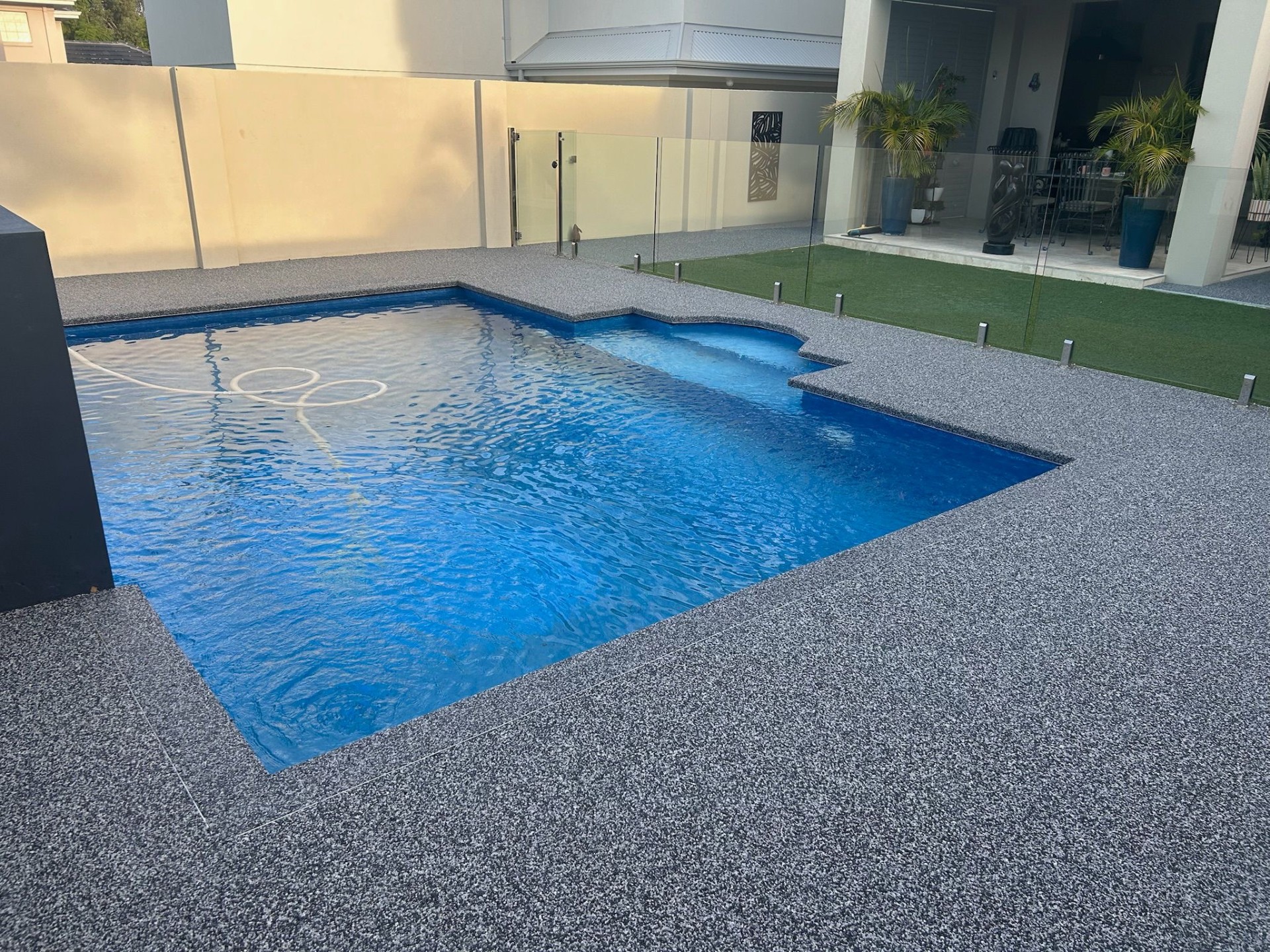 Resin bound grey flake pool surround with glass fencing