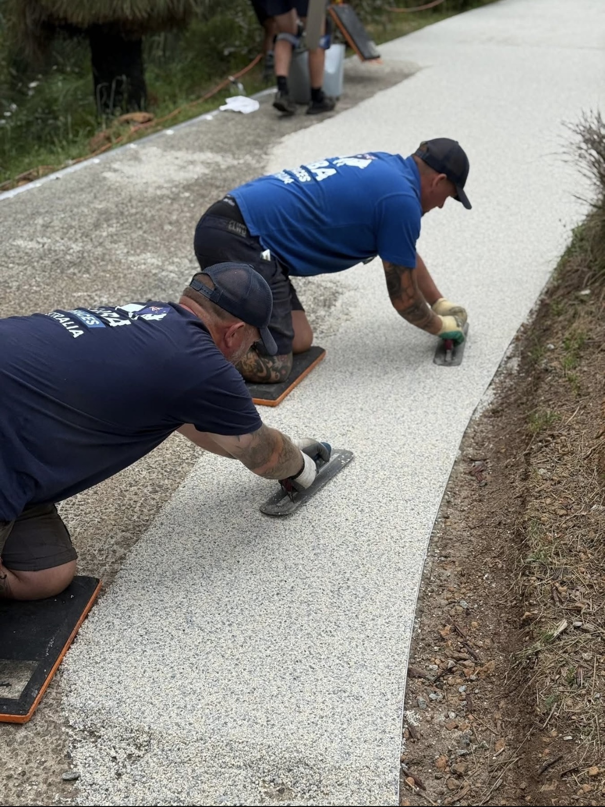 Two installers trowelling pathway on-site