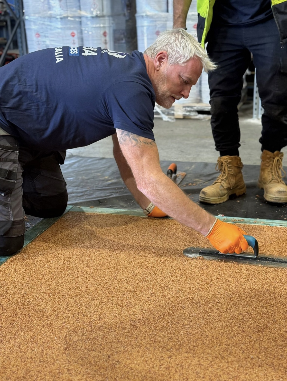 Trainee trowelling resin bound aggregate in warehouse